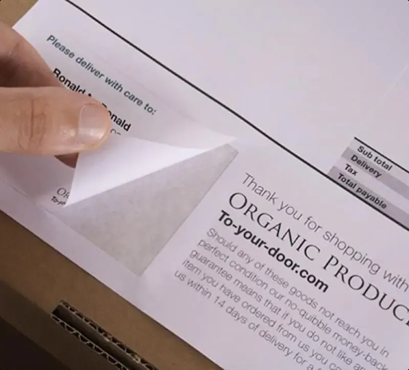 An image of an integrated form label combination with a person peeling the label off the page.
