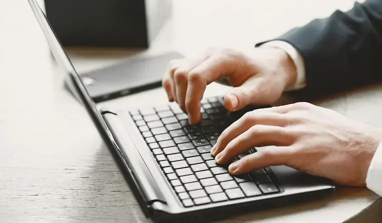 Work being done on a laptop, hands typing on a keyboard.